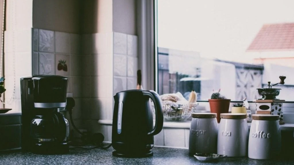 Koffiepot en waterkoker op aanrecht bij raam