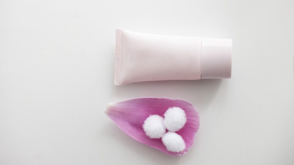 make up tube met roze bloemblaadje ernaast