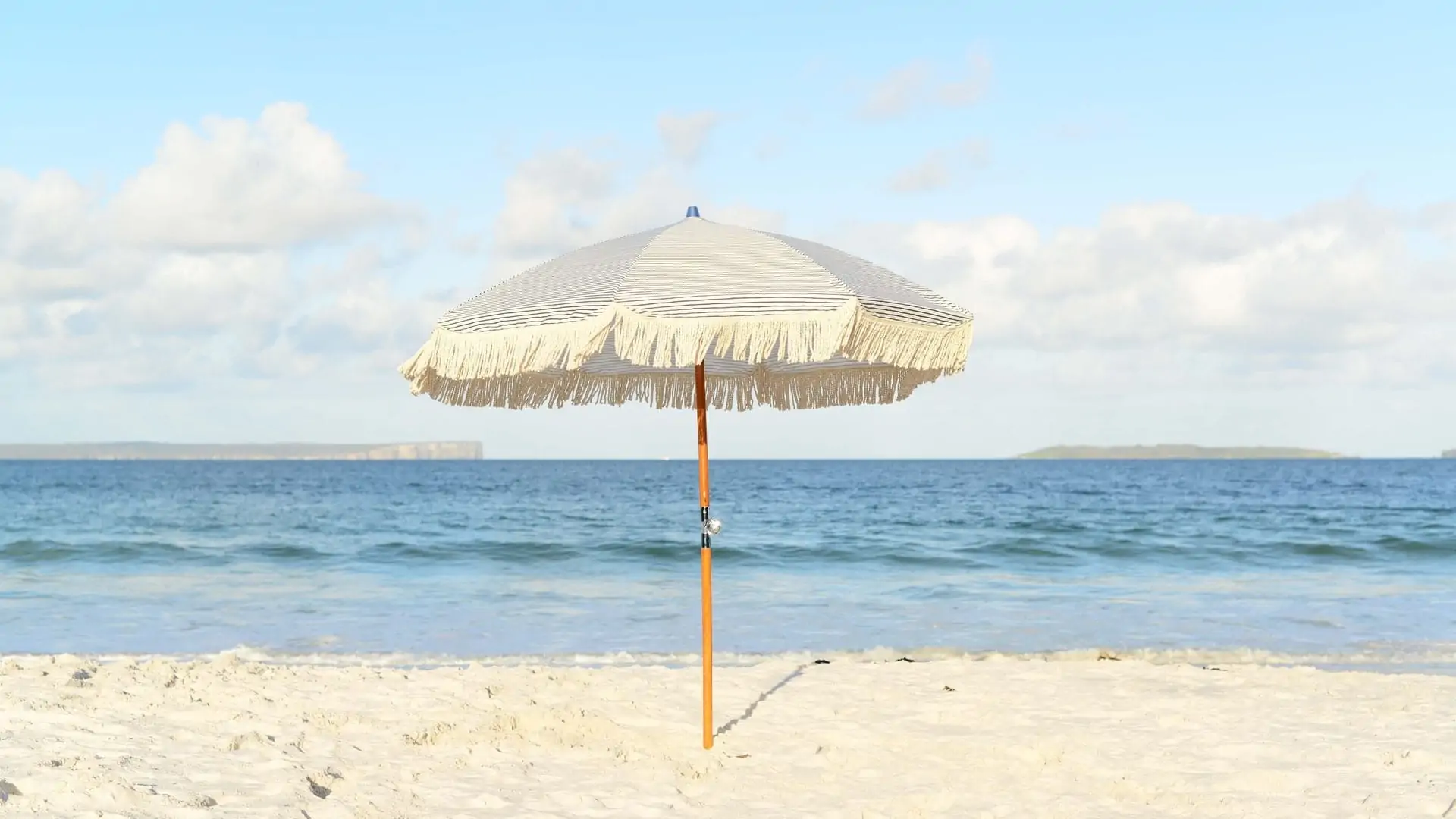 Parasol met volant op het strand, cremekleurig. 