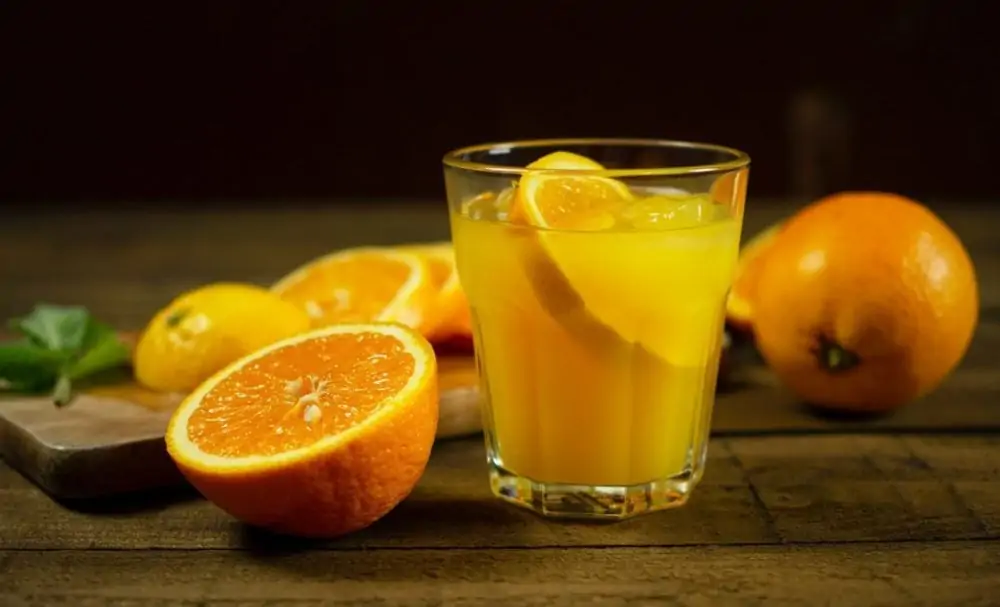 Glas sinaasappelsap met twee sinaasappels
