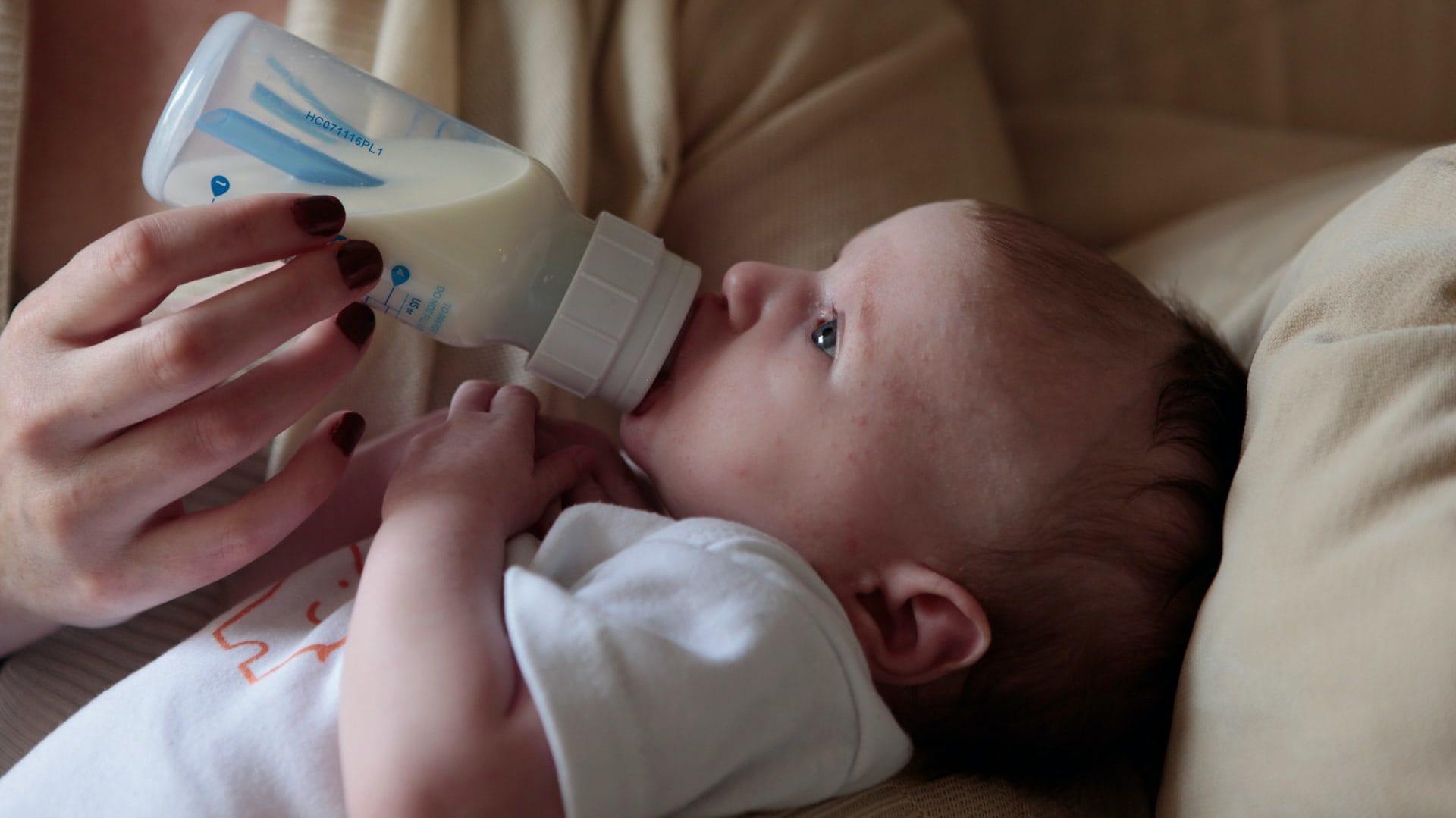 Pasgeboren baby krijgt de fles, zij-aanzicht
