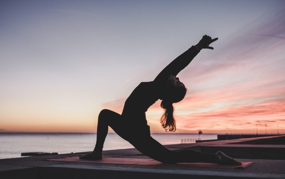 Yogapose met zonsondergang op de achtergrond