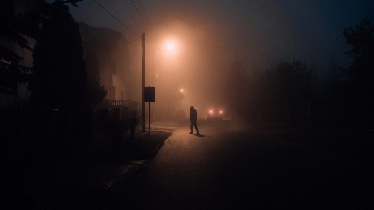 Persoon in een donkere straat.
