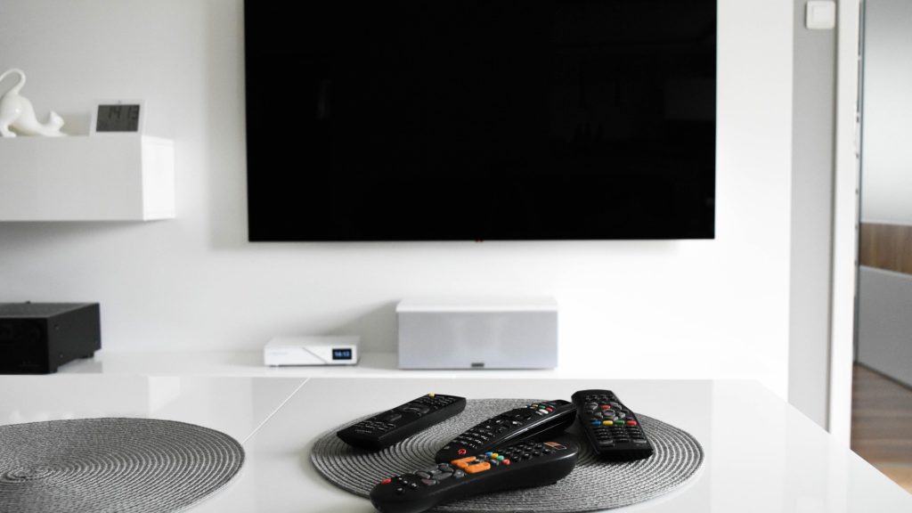 Meerdere afstandsbedieningen op een witte tafel voor een tv