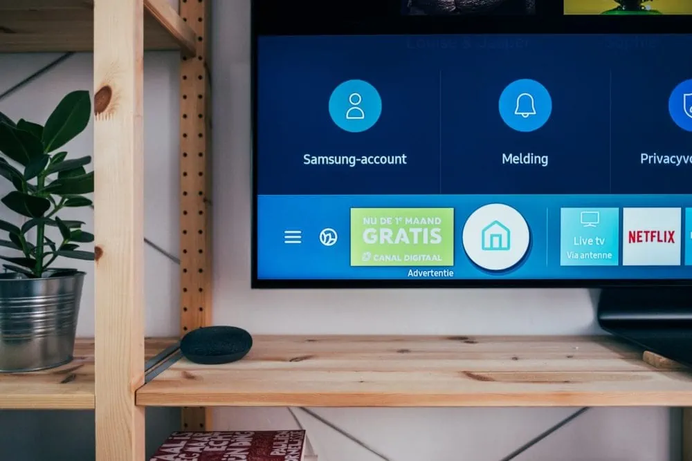 Tv in kast van hout, linkerhoek van de tv is zichtbaar met Nederlands smart-menu. Vooraanzicht